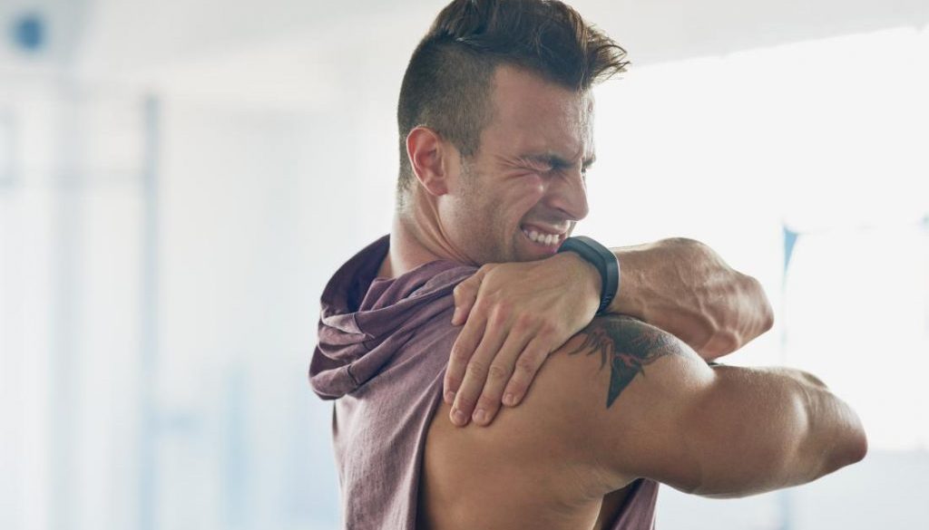 man-with-painful-shoulder-holding-it-and-grimacing