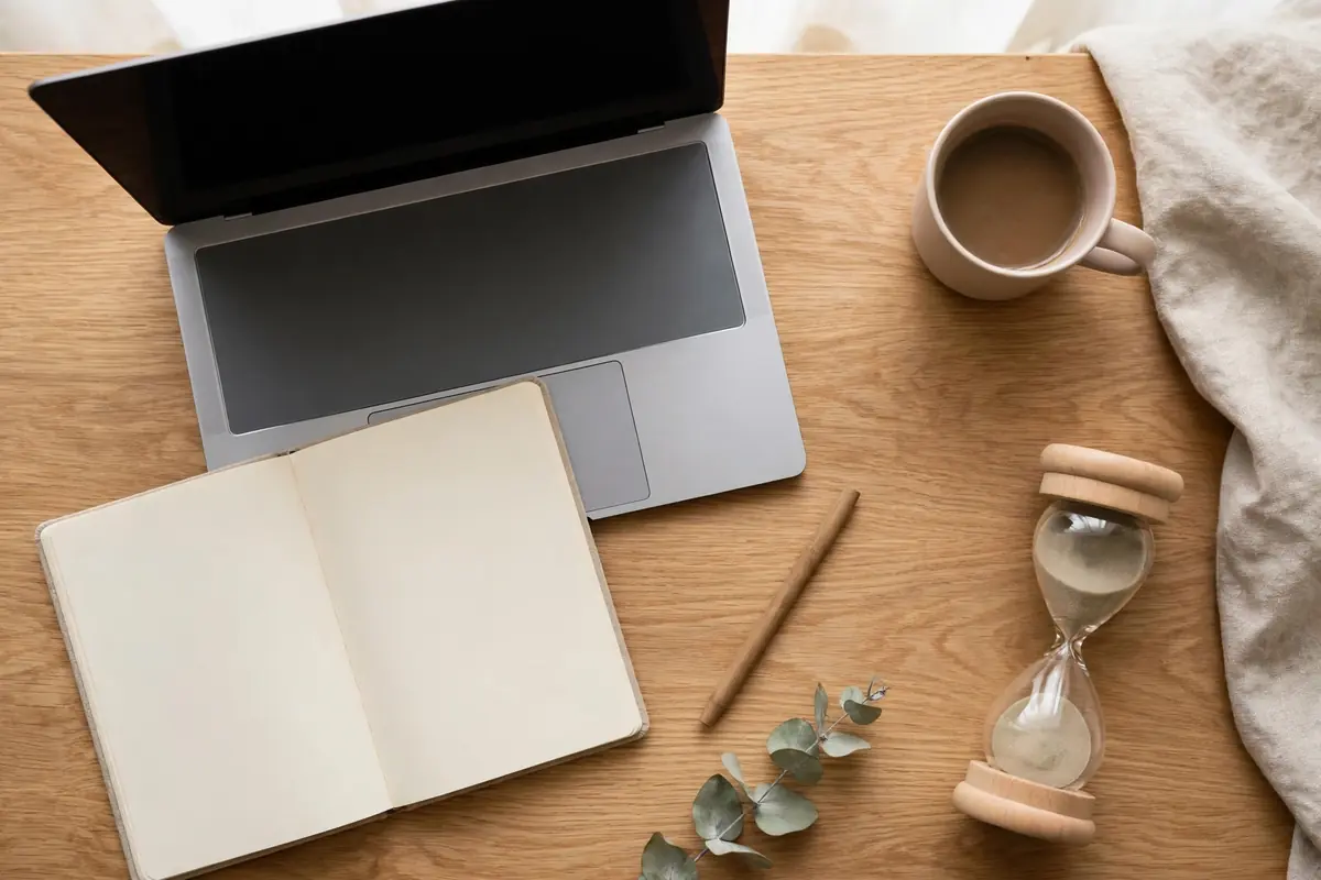 Overhead view of a tidy blogging workspace with laptop, notebook, and timer