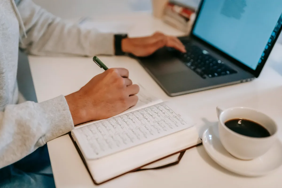 Writer planning blog content in a notebook beside a laptop