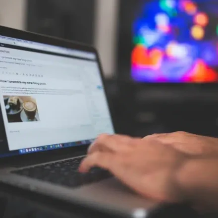 Person creating a blog post at a desk in front of a computer