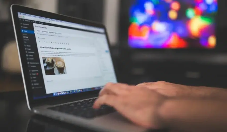 Person creating a blog post at a desk in front of a computer