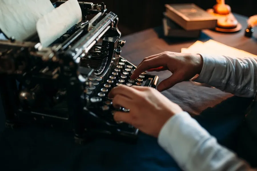 Close-up of hands typing an article draft on a desk