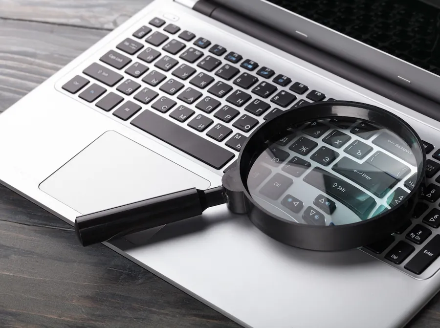 Magnifying glass resting on a laptop keyboard representing search